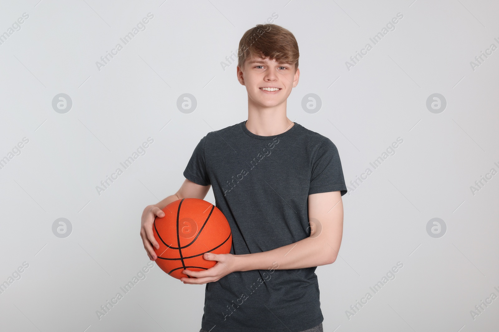 Photo of Teenage boy with basketball ball on light grey background