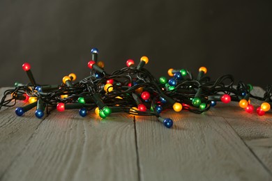 Photo of Beautiful glowing Christmas lights on wooden table against black background