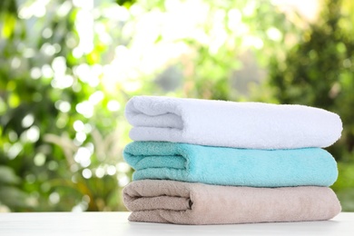 Stack of clean soft towels on table against blurred background. Space for text