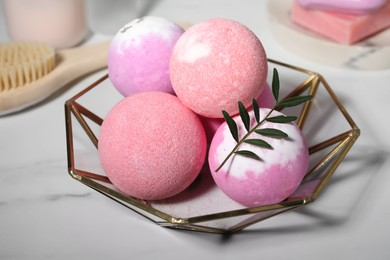 Beautiful aromatic bath bombs and green twig on white marble table, closeup