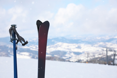 Photo of Ski and poles on beautiful snowy hill. Space for text