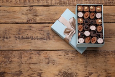 Open box of delicious chocolate candies on wooden table, top view. Space for text