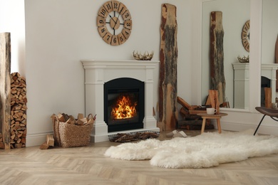 Photo of Beautiful fireplace and basket with firewood in contemporary room interior