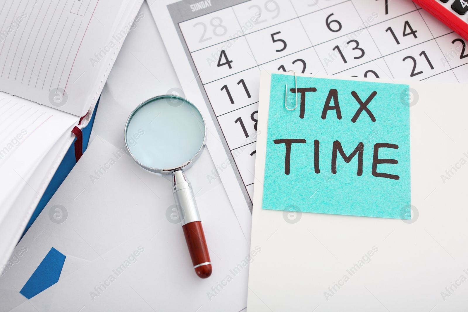 Photo of Flat lay composition with calendar and magnifying glass on table. Tax time