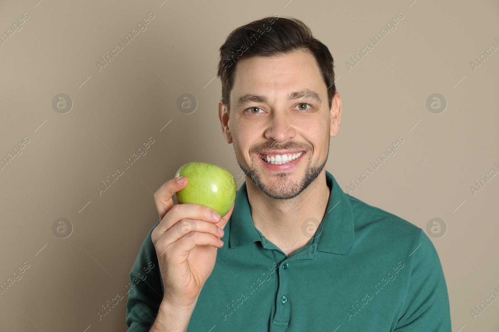 Photo of Smiling man with perfect teeth and green apple on color background