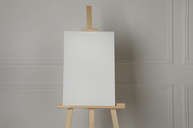 Photo of Wooden easel with blank canvas on light background