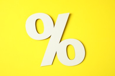 Photo of White percent sign on yellow background, top view