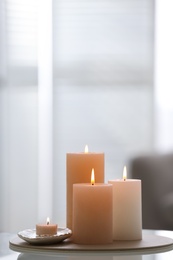 Burning candles on table indoors, space for text. Interior elements