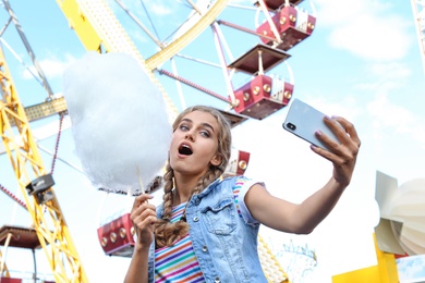Photo of Attractive woman taking selfie with cotton candy in amusement park