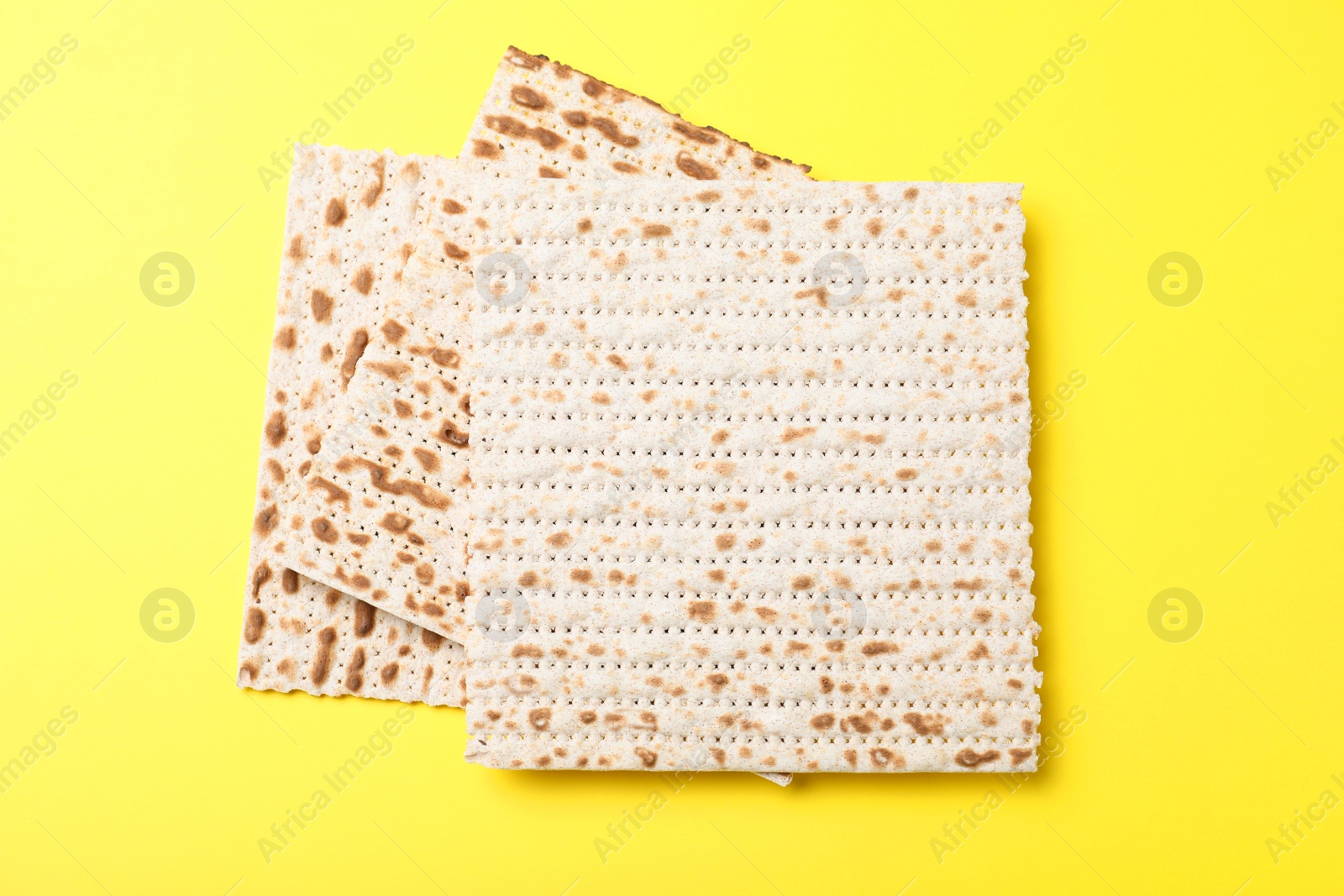 Photo of Traditional matzos on yellow background, flat lay