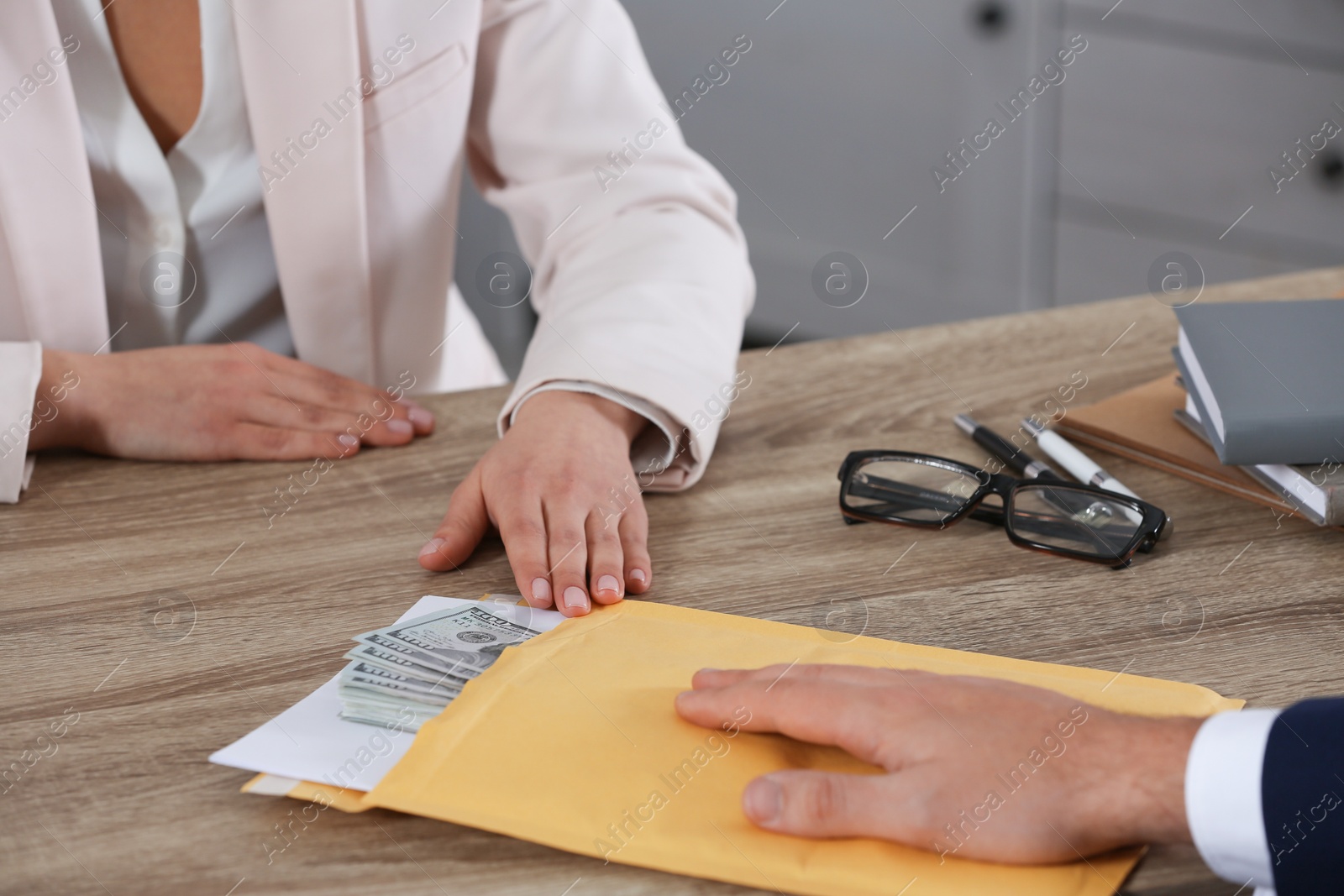 Photo of Man giving bribe to woman at table in office, closeup