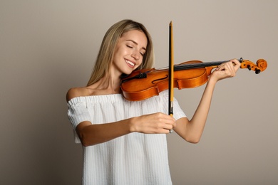Photo of Beautiful woman playing violin on beige background