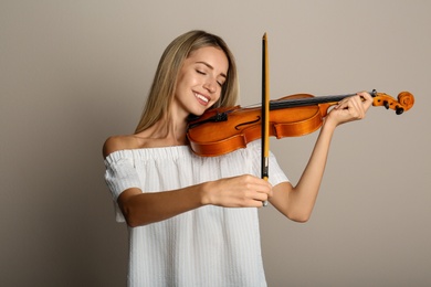 Beautiful woman playing violin on beige background