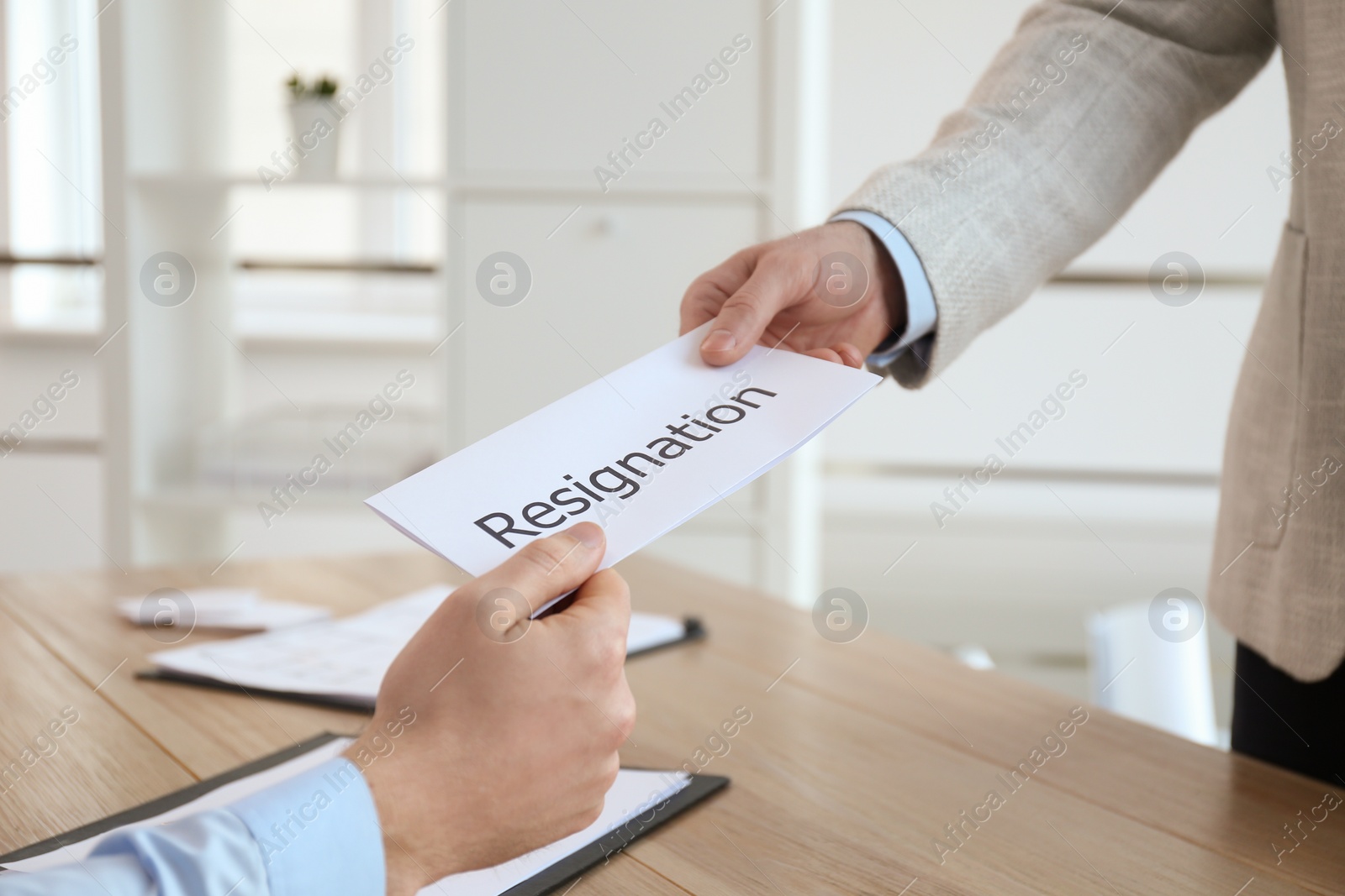 Photo of Employee giving resignation letter to boss in office, closeup