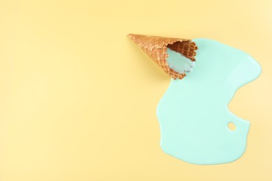 Photo of Melted ice cream and wafer cone on beige background, top view. Space for text
