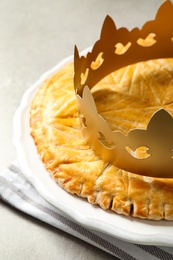 Traditional galette des Rois with paper crown on table, closeup