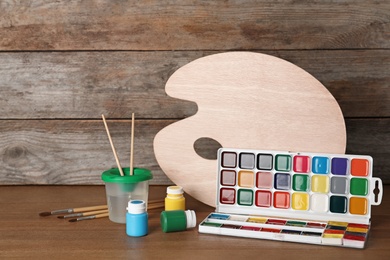 Photo of Set of painting tools for children on table near wooden wall. Space for text