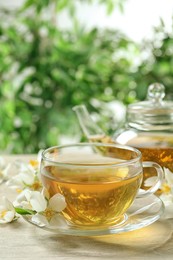 Photo of Aromatic jasmine tea and fresh flowers on wooden table