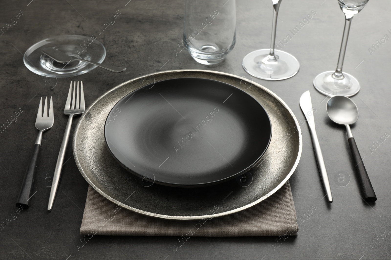 Photo of Stylish setting with cutlery, glasses and plates on black table