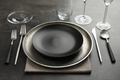 Photo of Stylish setting with cutlery, glasses and plates on black table