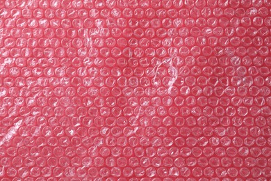 Photo of Transparent bubble wrap on red background, top view