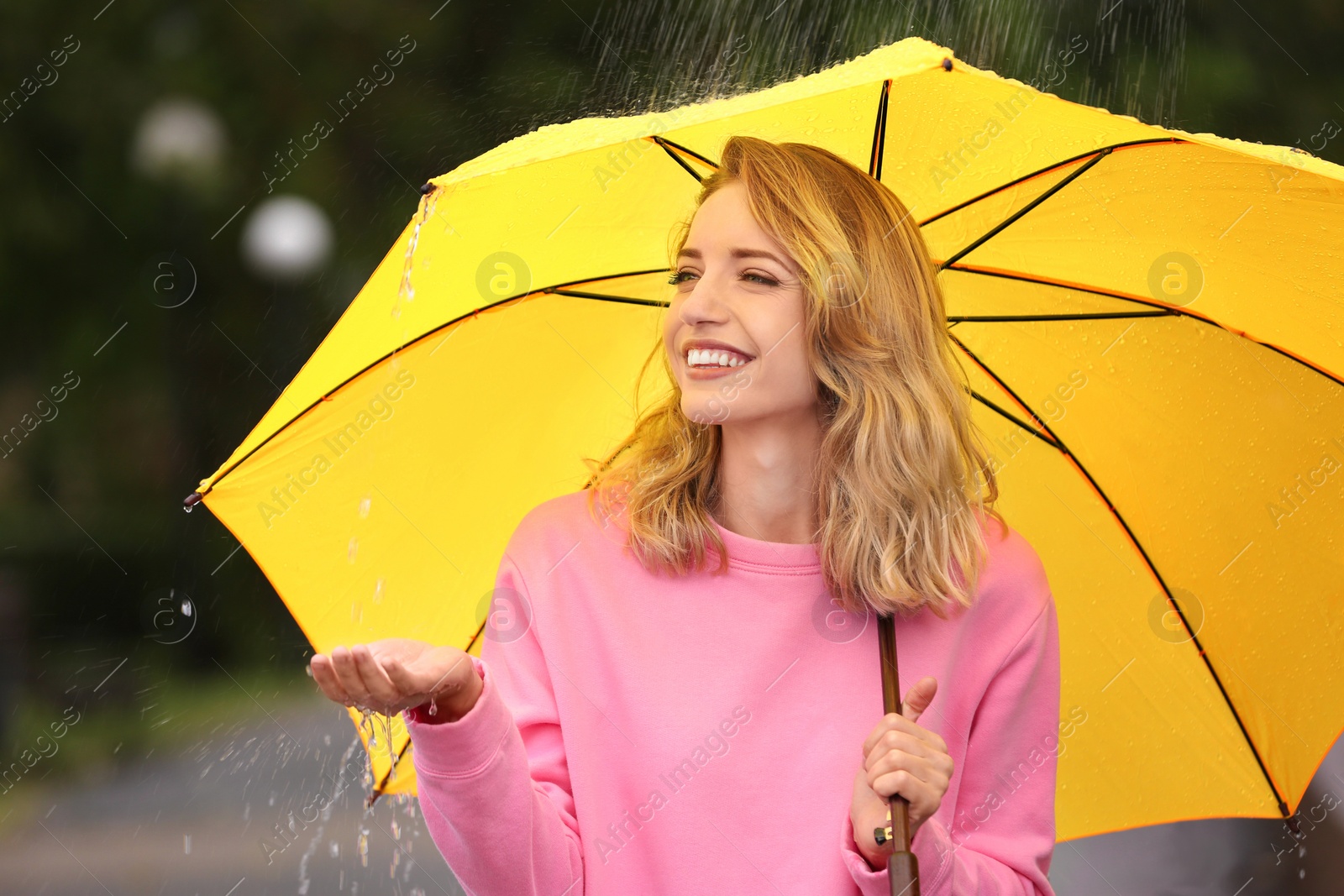 Photo of Happy young woman with bright umbrella under rain outdoors