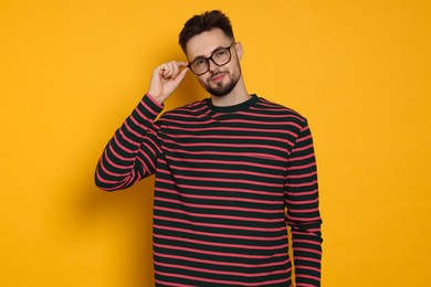 Photo of Handsome man in striped sweatshirt and eyeglasses on yellow background