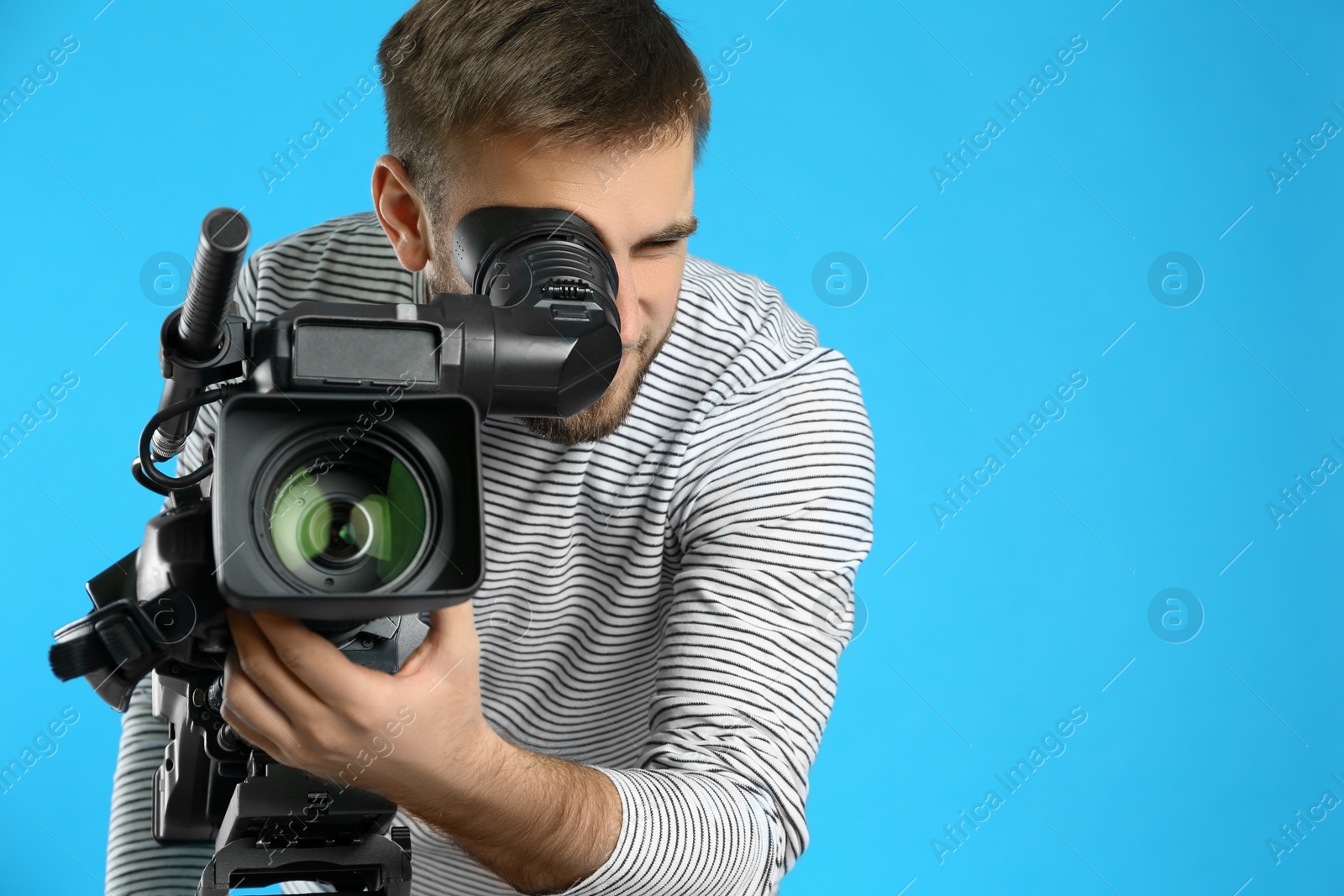 Photo of Operator with professional video camera on blue background