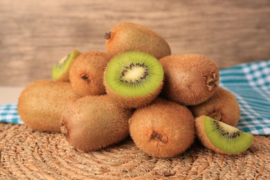 Photo of Heap of whole and cut fresh kiwis on wicker mat