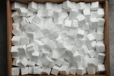 Cardboard box filled with polystyrene styrofoam pieces on grey background, top view