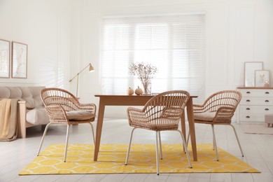 Photo of Dining room interior with wooden table and wicker chairs