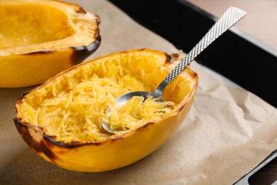 Photo of Halves of cooked spaghetti squash and spoon on baking sheet, closeup