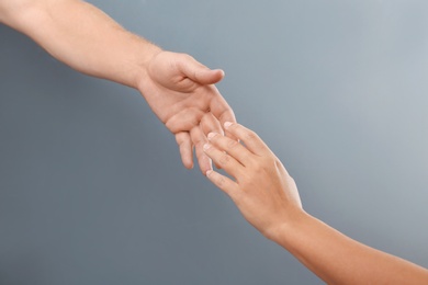 Photo of Man and woman giving each other hands on gray background. Concept of support and help