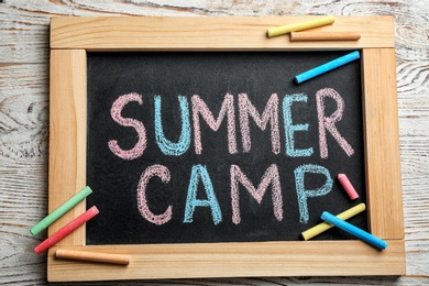 Text "SUMMER CAMP" on small blackboard and colorful chalk, top view