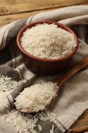 Photo of Raw basmati rice in bowl and spoon on table