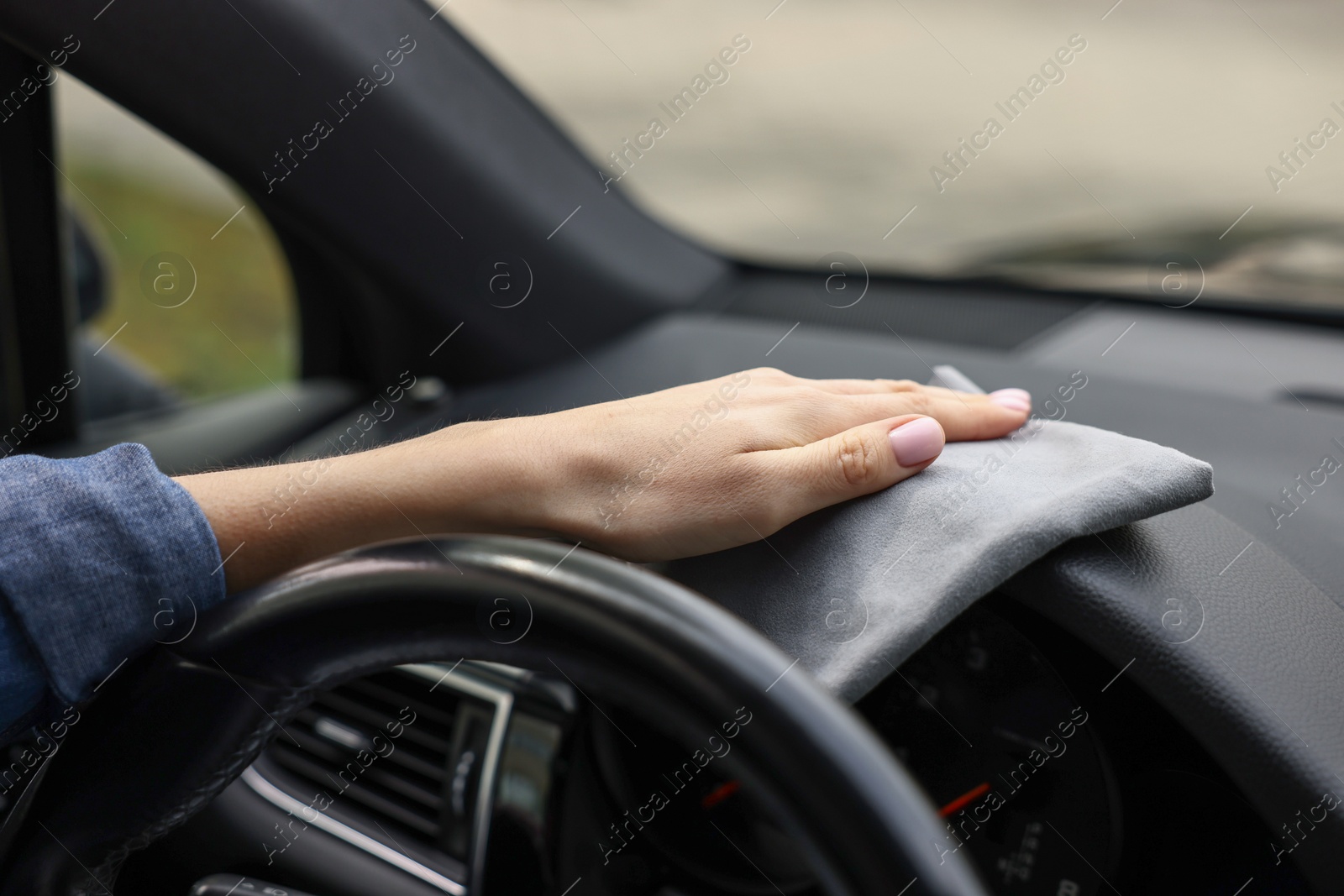 Photo of Woman wiping her modern car with rag, closeup