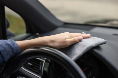 Woman wiping her modern car with rag, closeup