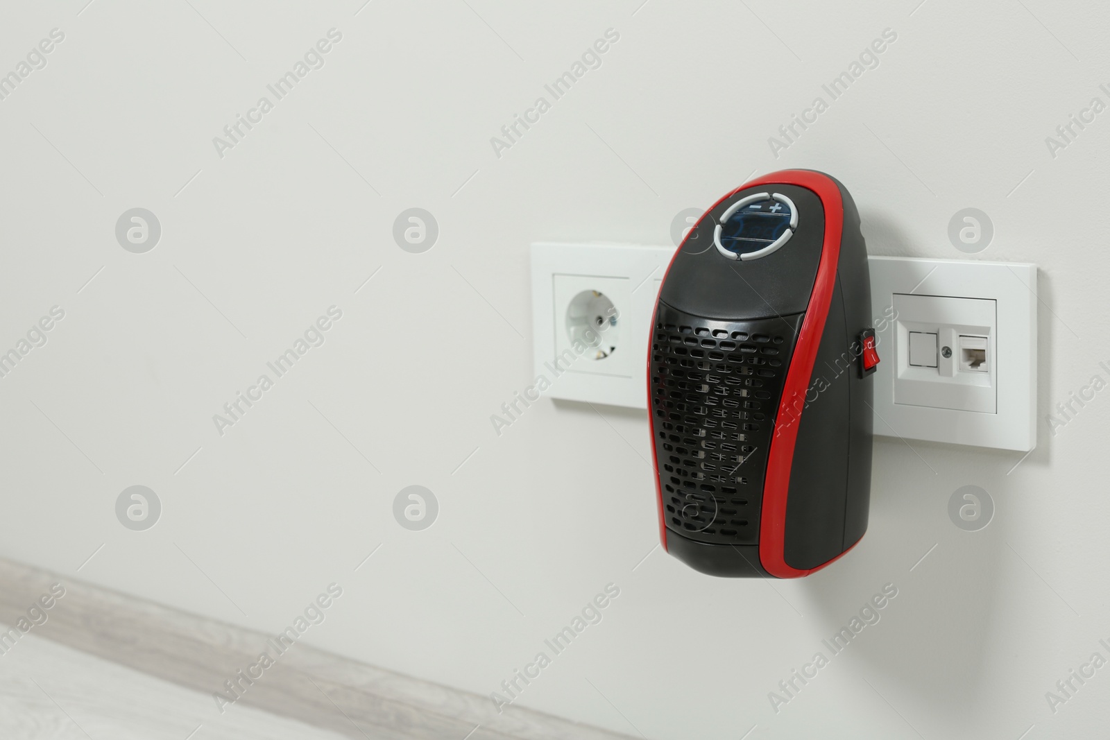 Photo of Compact electric heater charging from socket indoors, space for text