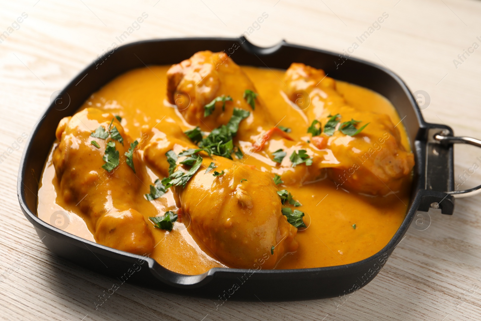 Photo of Tasty chicken curry with parsley on wooden table, closeup