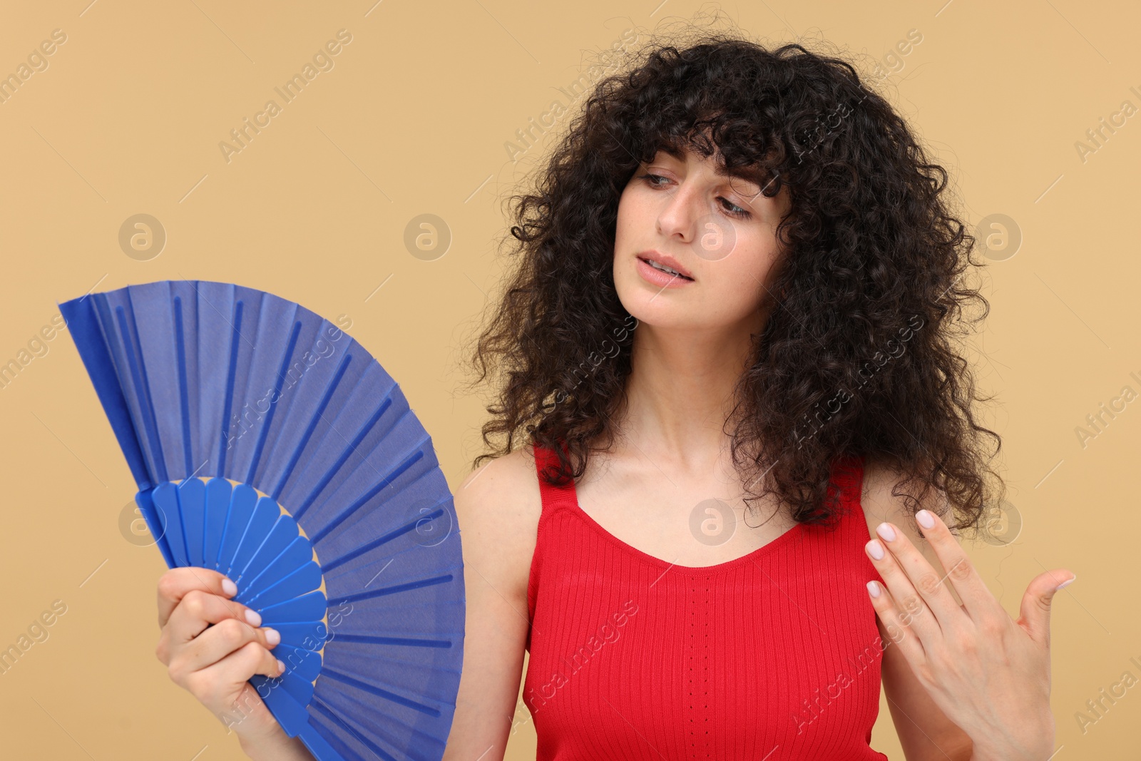 Photo of Woman with hand fan suffering from heat on beige background