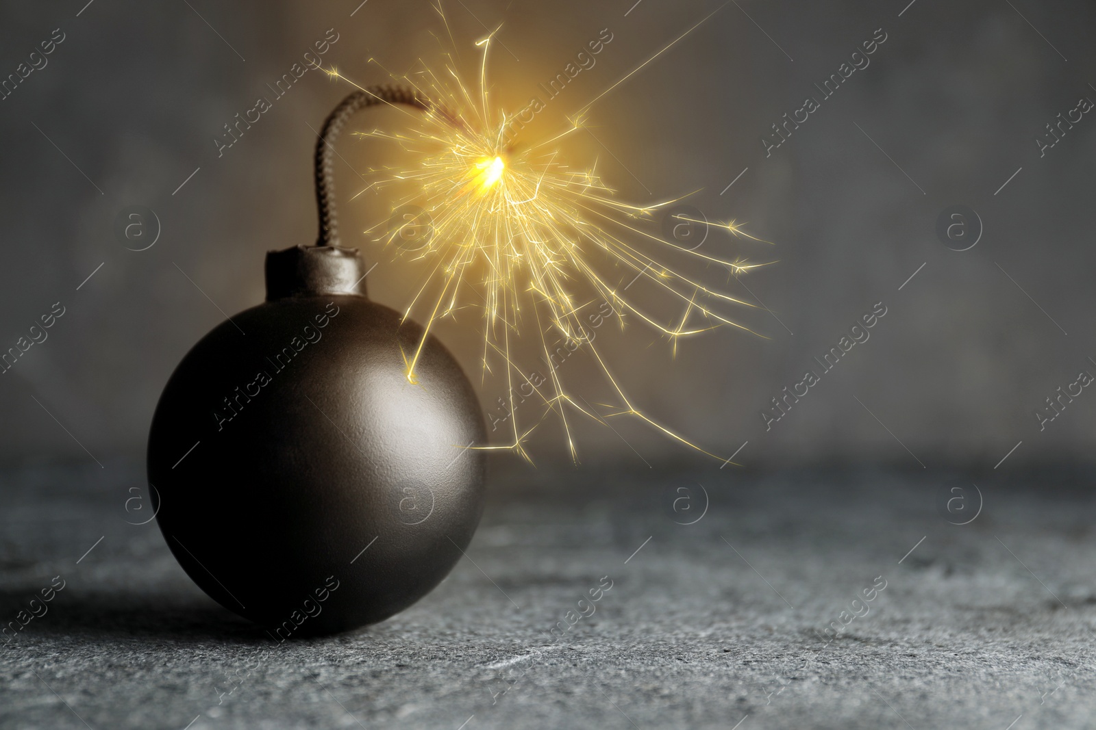 Image of Old fashioned black bomb with lit fuse on grey table, space for text