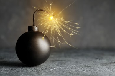 Image of Old fashioned black bomb with lit fuse on grey table, space for text