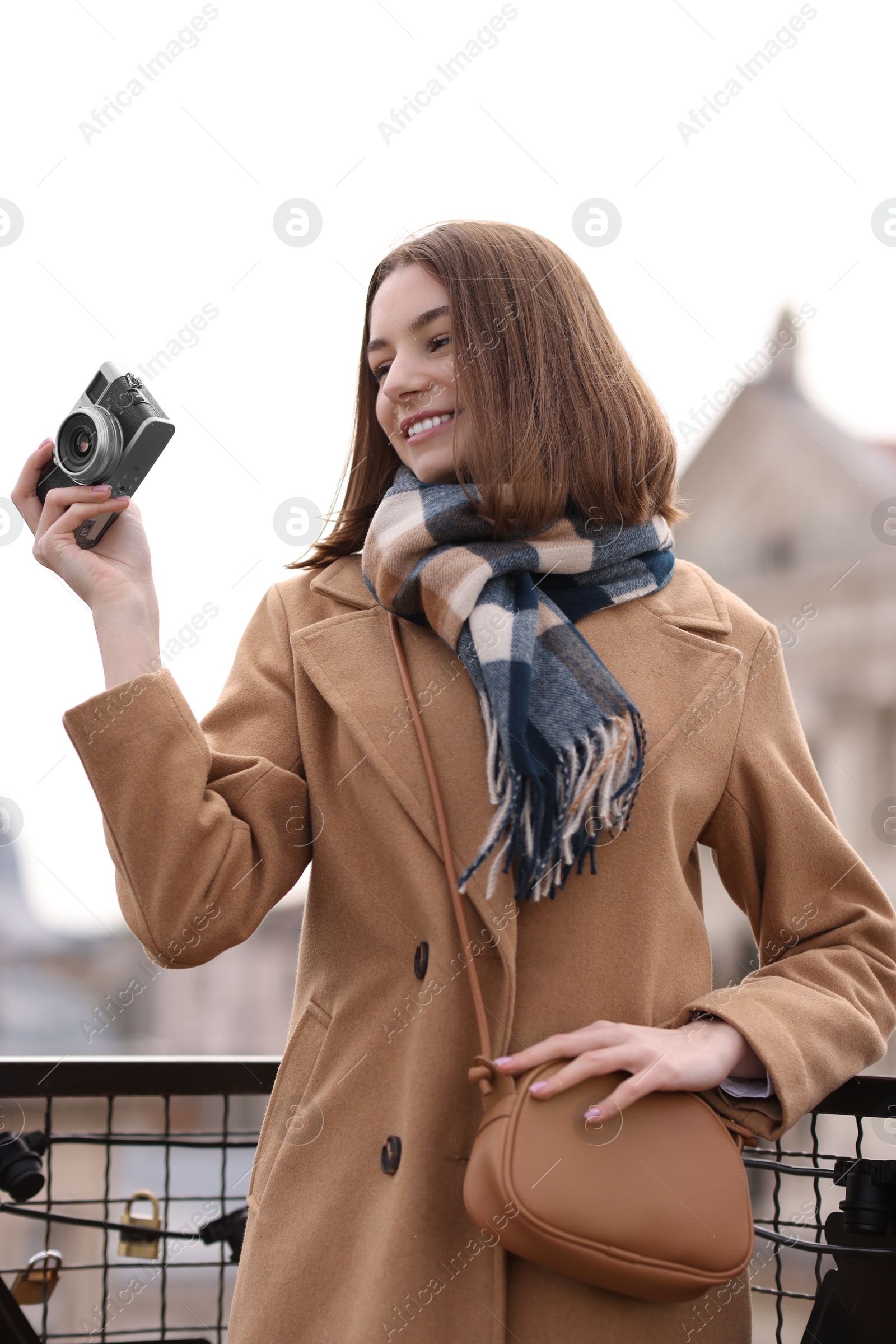 Photo of Beautiful woman in warm scarf with vintage camera outdoors