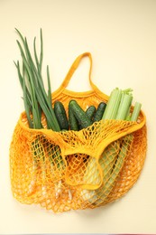 Photo of String bag with different vegetables on beige background, top view