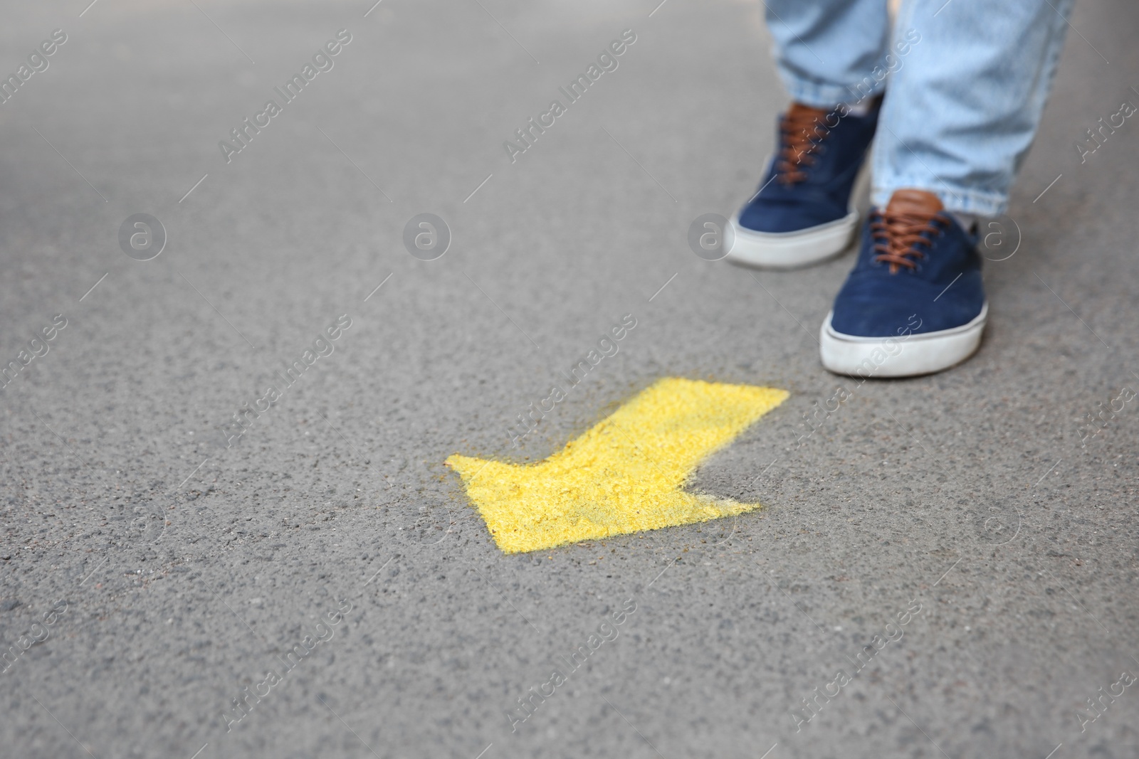 Photo of Man standing near arrow on asphalt, closeup