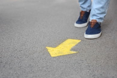 Photo of Man standing near arrow on asphalt, closeup