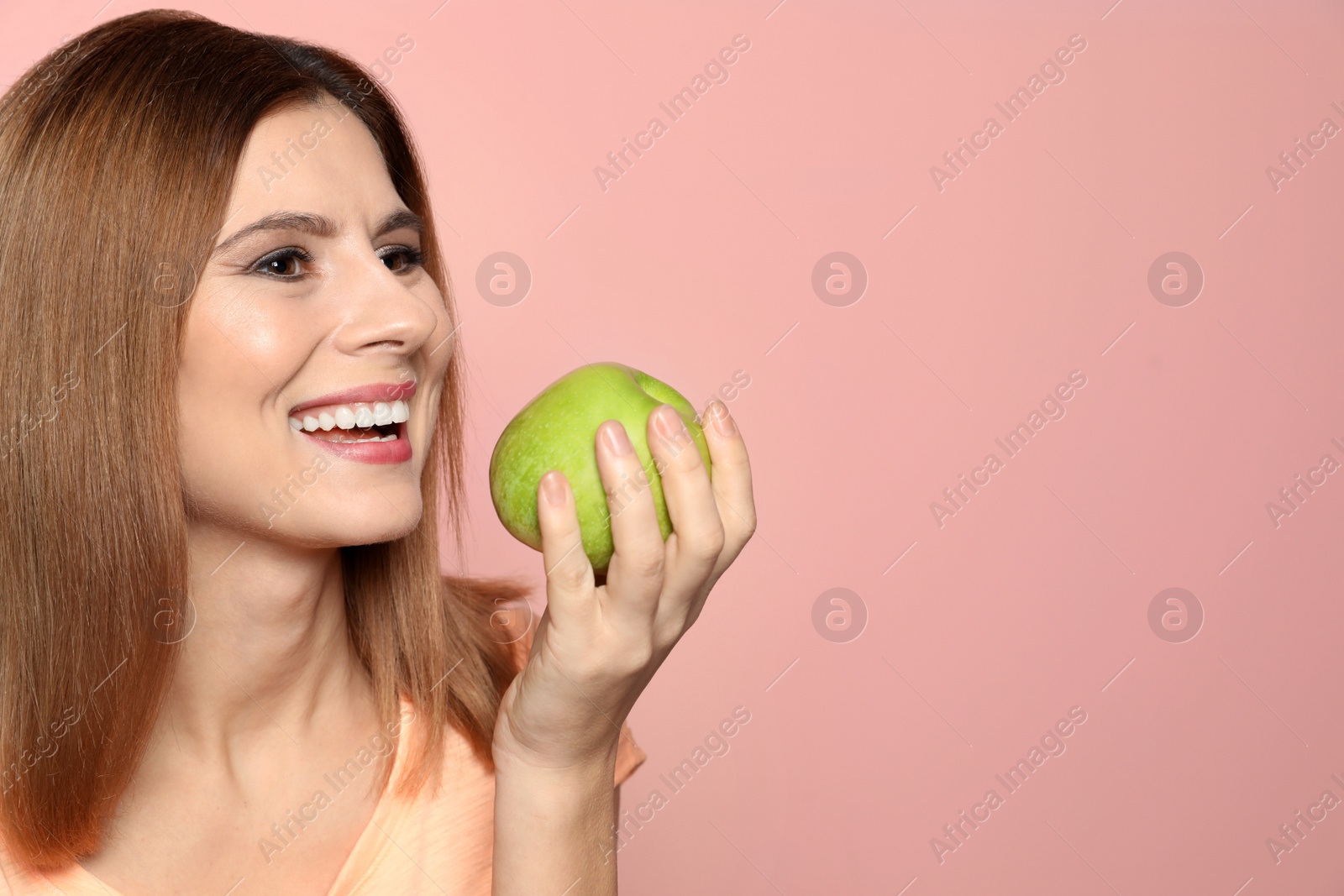 Photo of Smiling woman with perfect teeth and green apple on color background. Space for text