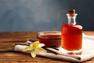 Photo of Aromatic homemade vanilla extract on wooden table