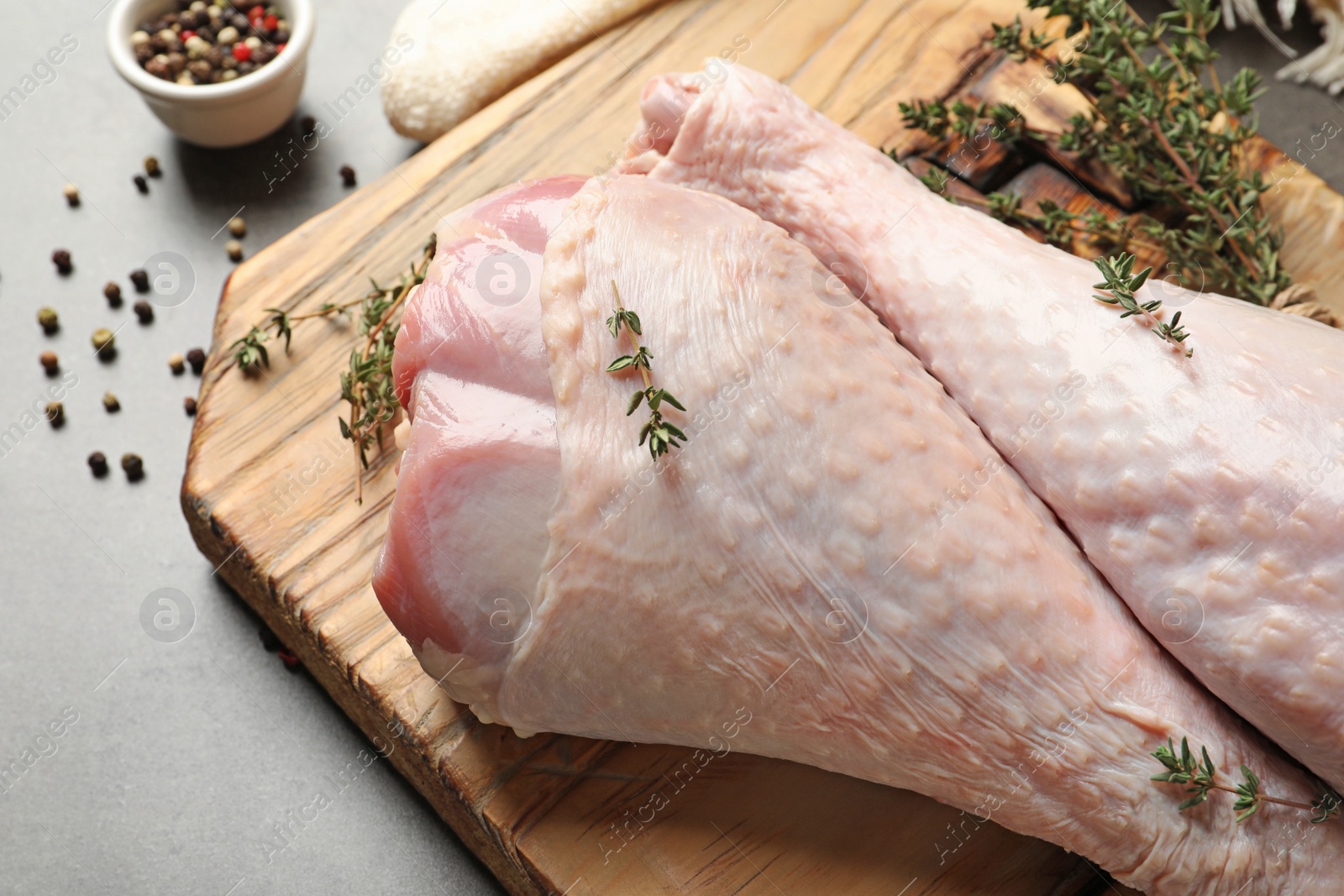 Photo of Board with raw turkey drumsticks, spices and thyme on table, closeup