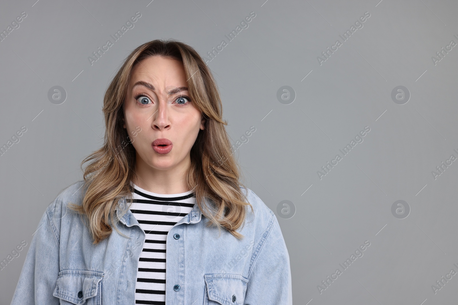 Photo of Portrait of surprised woman on grey background. Space for text